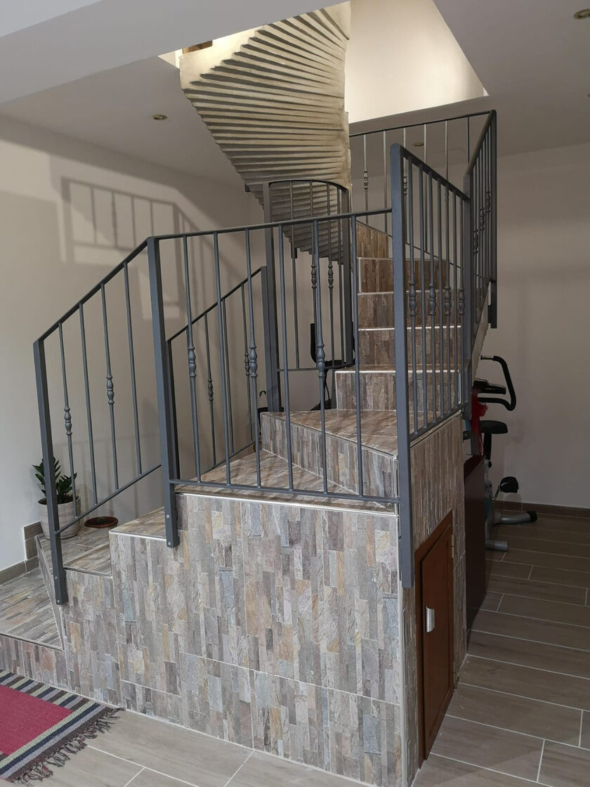Scala rivestita in pietra con ringhiera in ferro grigio